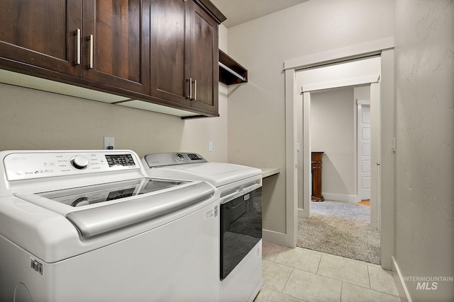 laundry area featuring light tile patterned floors, independent washer and dryer, cabinet space, and baseboards