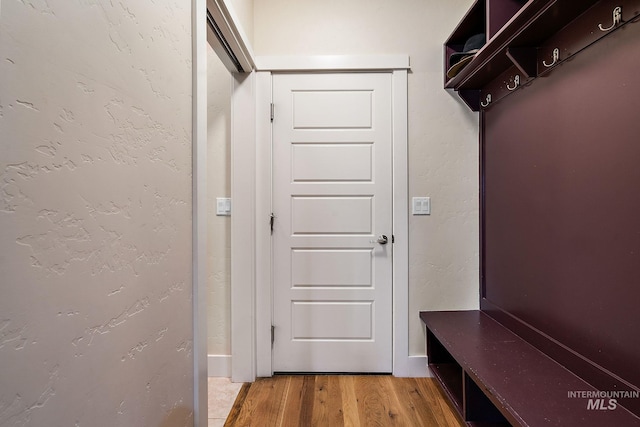 mudroom featuring light wood-type flooring, a textured wall, and baseboards