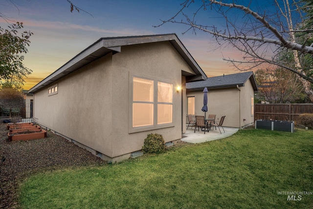 rear view of property featuring a patio area, fence, a garden, and stucco siding