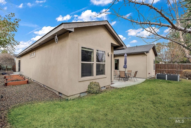 rear view of property featuring a garden, a lawn, fence, a patio area, and stucco siding