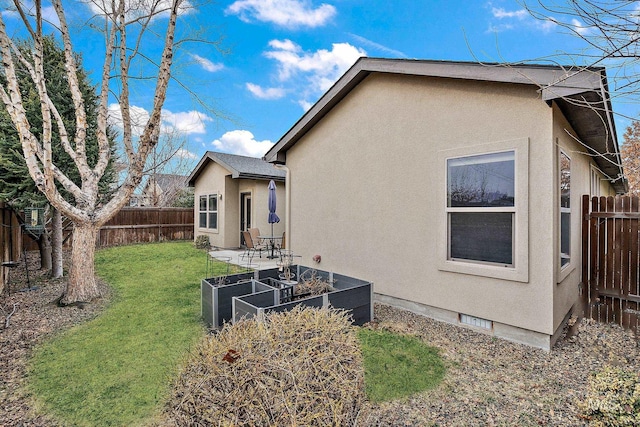 back of property featuring a yard, a fenced backyard, a garden, and stucco siding