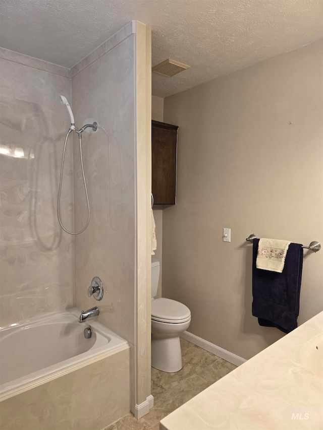 bathroom with a textured ceiling, tiled shower / bath combo, and toilet