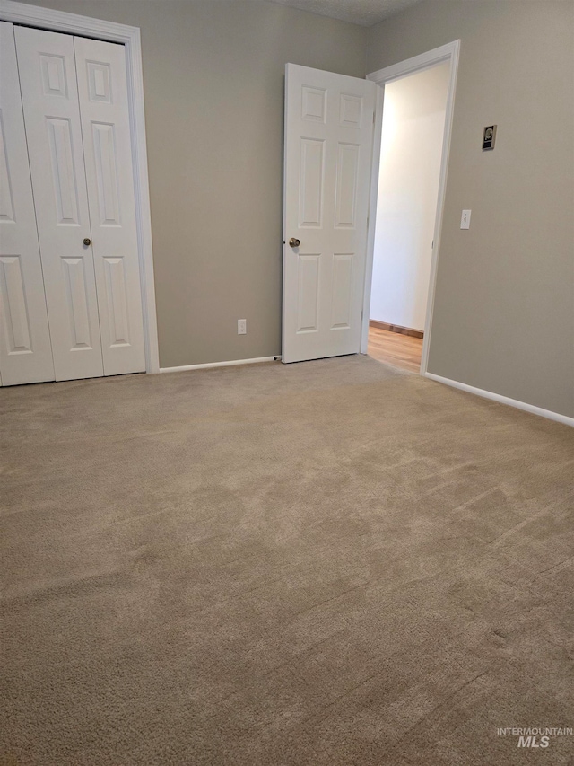 unfurnished bedroom featuring light carpet and a closet