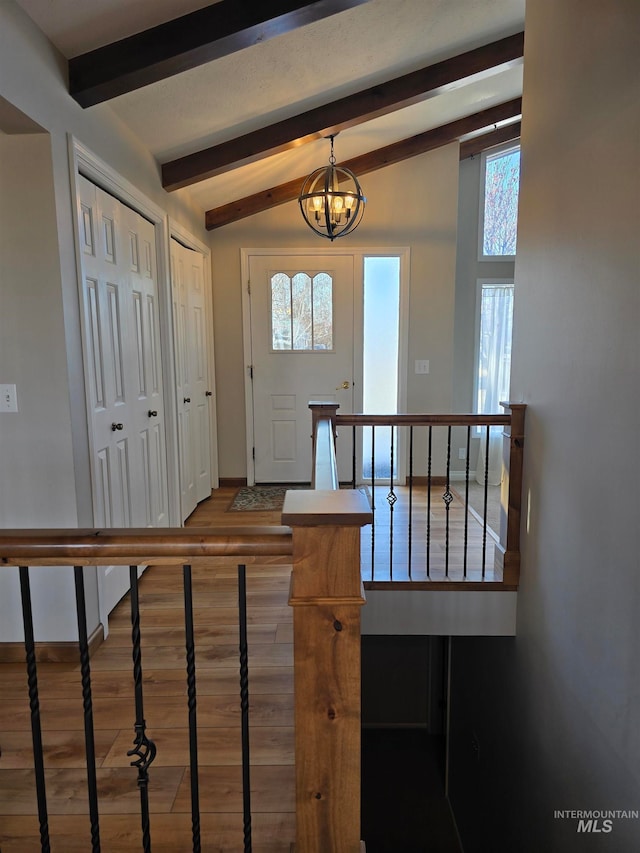 entrance foyer with hardwood / wood-style floors, vaulted ceiling with beams, and a notable chandelier