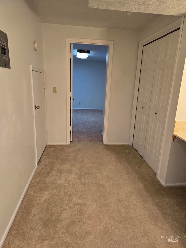 hallway with a textured ceiling and light carpet