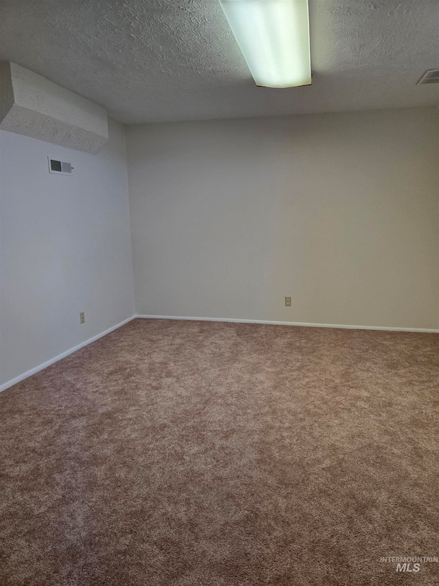 empty room with carpet and a textured ceiling