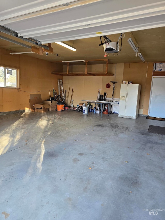 garage featuring a garage door opener and white fridge with ice dispenser