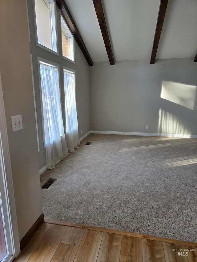 empty room with lofted ceiling with beams and light wood-type flooring