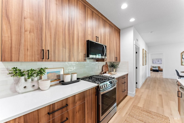 kitchen featuring decorative backsplash, appliances with stainless steel finishes, and light hardwood / wood-style flooring