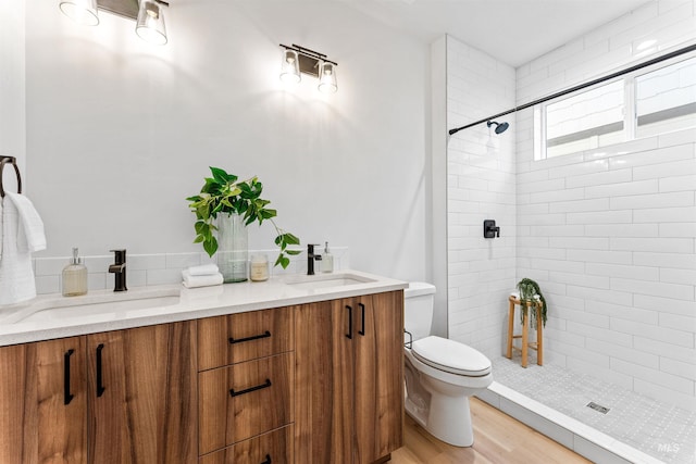 bathroom featuring hardwood / wood-style floors, vanity, toilet, and tiled shower