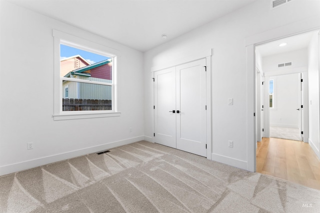 unfurnished bedroom featuring a closet and light colored carpet