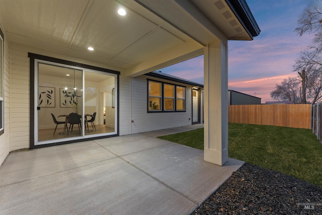 patio terrace at dusk featuring a lawn