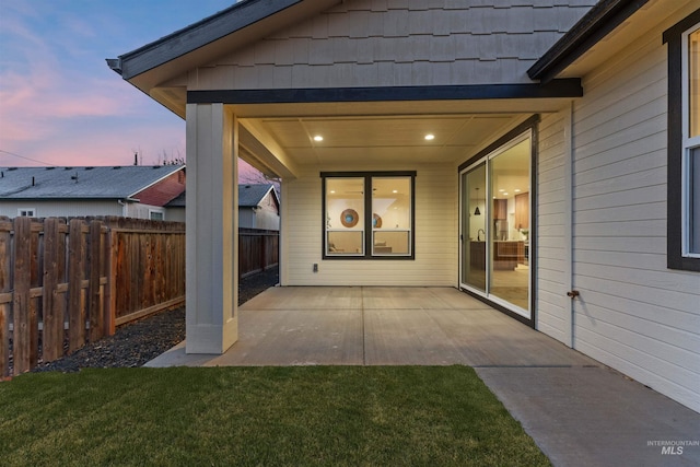 patio terrace at dusk featuring a yard