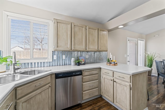 kitchen featuring light brown cabinets, a peninsula, a sink, dishwasher, and dark wood finished floors