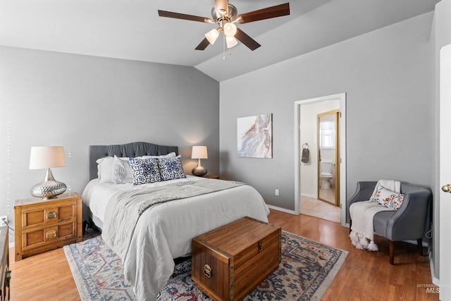 bedroom featuring lofted ceiling, light wood-type flooring, connected bathroom, and baseboards