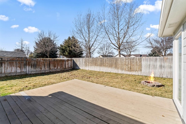 deck with an outdoor fire pit, a lawn, and a fenced backyard