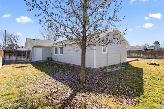 back of house featuring a fenced backyard, a yard, and central air condition unit