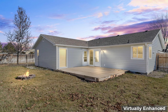 back of house with roof with shingles, a yard, a fenced backyard, a fire pit, and a wooden deck