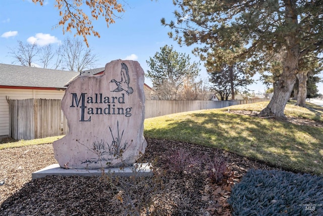 community / neighborhood sign with fence and a lawn