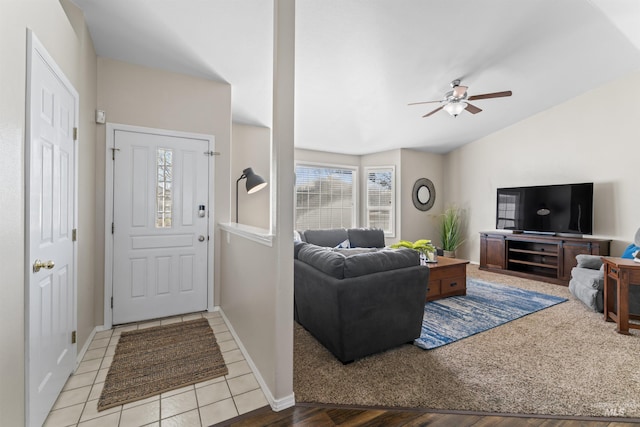 living area with lofted ceiling, tile patterned flooring, baseboards, and a ceiling fan