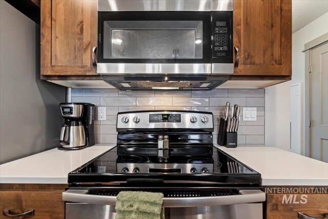 302 Broken Crk, Mccall, ID 83638 - kitchen with appliances with stainless steel finishes, brown cabinets, tasteful backsplash, and light countertops