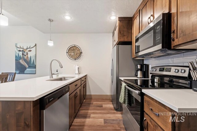 302 Broken Crk, Mccall, ID 83638 - kitchen featuring stainless steel appliances, a sink, a peninsula, light wood-style flooring, and baseboards