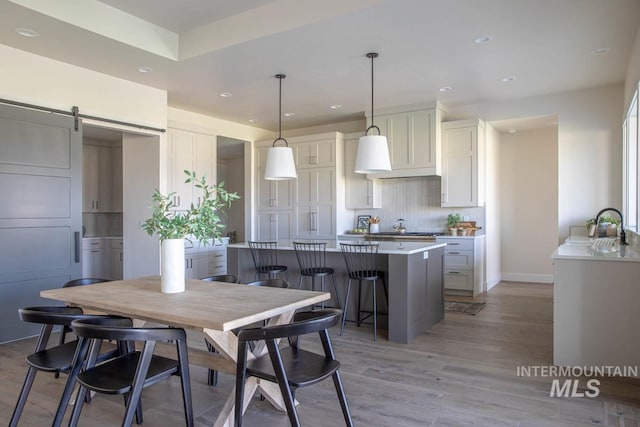 dining area with a barn door, recessed lighting, light wood-style floors, and baseboards