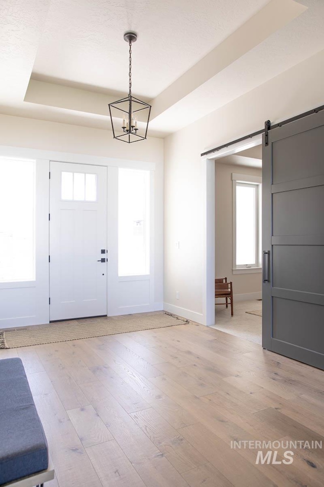 entryway with baseboards, a barn door, and light wood finished floors