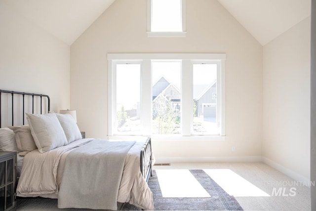 carpeted bedroom with visible vents, high vaulted ceiling, and baseboards