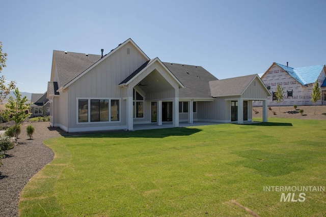 11179 N Elk Ridge Way, Boise, ID 83714 - rear view of house featuring board and batten siding, a lawn, a shingled roof, and a patio area