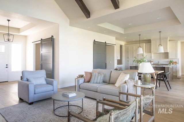 living room featuring a raised ceiling, a barn door, and light wood-type flooring
