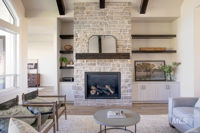 living area with beamed ceiling, built in features, and light wood-style flooring