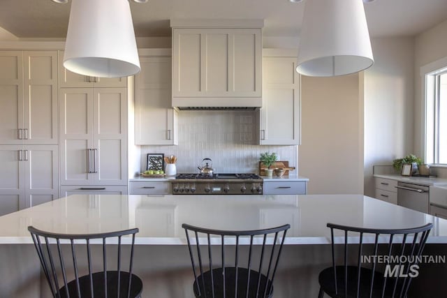 kitchen with a kitchen breakfast bar, tasteful backsplash, appliances with stainless steel finishes, light countertops, and a kitchen island