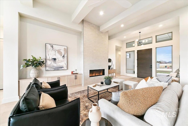 living room with beamed ceiling, a notable chandelier, and a fireplace