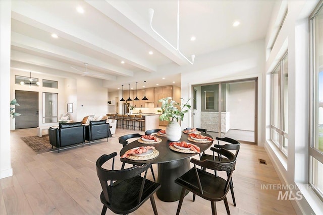 dining area featuring beamed ceiling and light hardwood / wood-style flooring