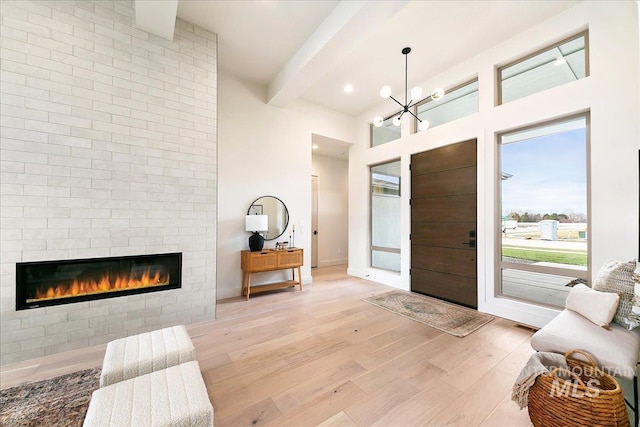 entrance foyer featuring beamed ceiling, a notable chandelier, and light hardwood / wood-style floors