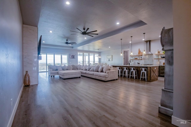 living room with a textured ceiling, hardwood / wood-style flooring, ceiling fan, and sink