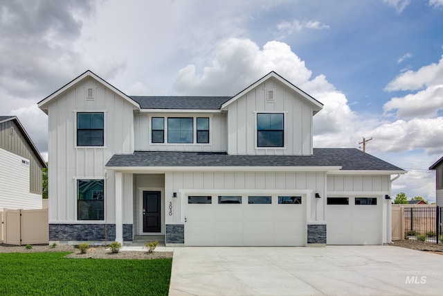 modern farmhouse featuring concrete driveway, a shingled roof, board and batten siding, and fence