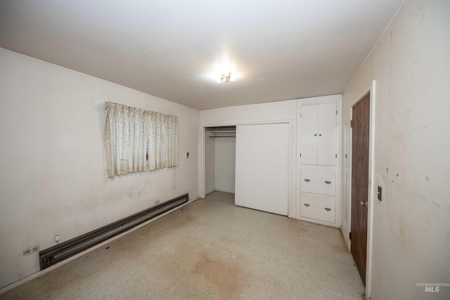 unfurnished bedroom with a baseboard heating unit and a closet