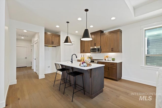 2316 E Valensole St, Meridian, ID 83642 - kitchen featuring appliances with stainless steel finishes, baseboards, light wood-style floors, tasteful backsplash, and light countertops