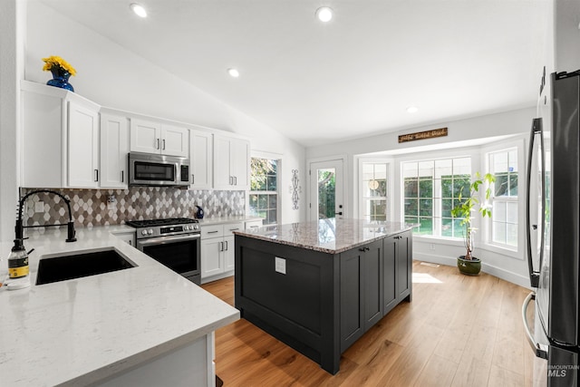3832 W Aspen Creek Ct, Meridian, ID 83642 - kitchen featuring appliances with stainless steel finishes, a sink, vaulted ceiling, decorative backsplash, and white cabinetry