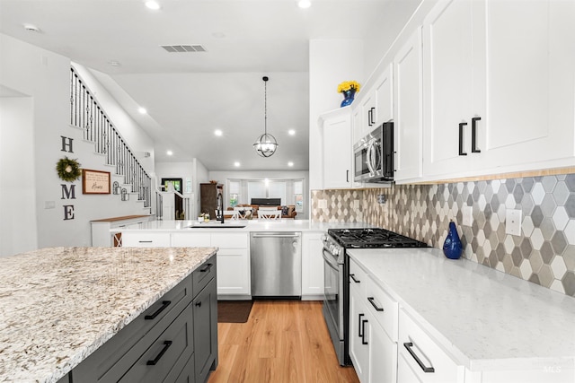 3832 W Aspen Creek Ct, Meridian, ID 83642 - kitchen featuring appliances with stainless steel finishes, a sink, a peninsula, light wood-style flooring, and tasteful backsplash