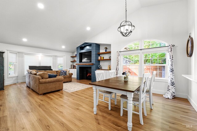 3832 W Aspen Creek Ct, Meridian, ID 83642 - dining area featuring a large fireplace, plenty of natural light, light wood finished floors, a chandelier, and high vaulted ceiling