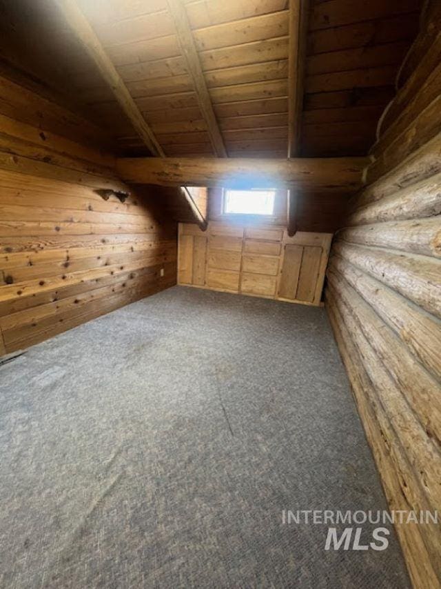 bonus room with wood ceiling, beam ceiling, rustic walls, and dark colored carpet