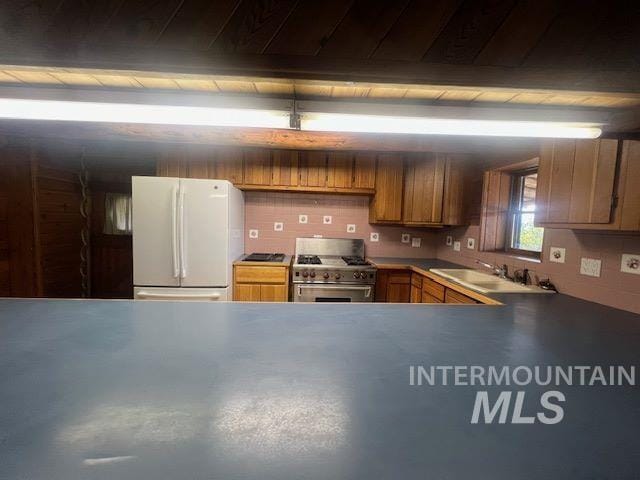 kitchen featuring sink, white refrigerator, high end stove, decorative backsplash, and beamed ceiling