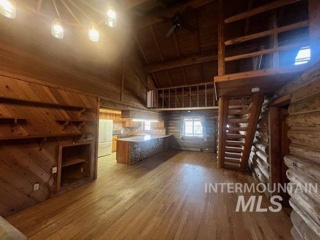 kitchen featuring hardwood / wood-style floors, high vaulted ceiling, rustic walls, white fridge, and beam ceiling