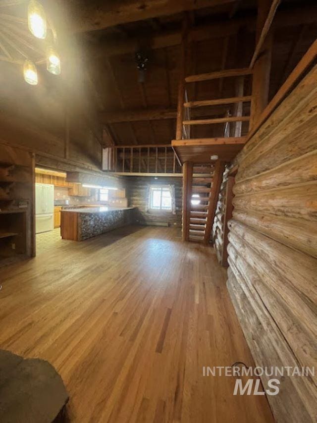 bonus room with log walls, a towering ceiling, and hardwood / wood-style flooring