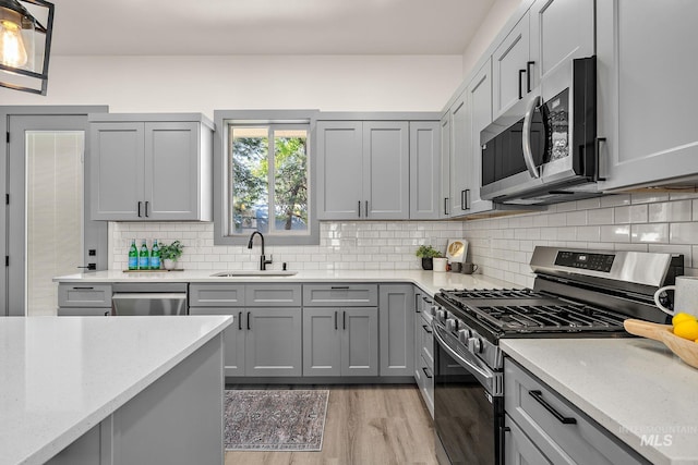 6825 W Ustick, Boise, ID 83704 - kitchen with gray cabinets, appliances with stainless steel finishes, light stone countertops, a sink, and light wood-style floors