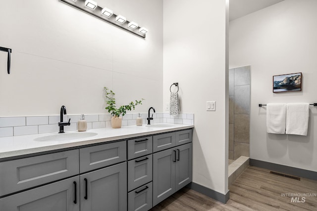 6825 W Ustick, Boise, ID 83704 - bathroom with baseboards, decorative backsplash, a sink, and wood finished floors