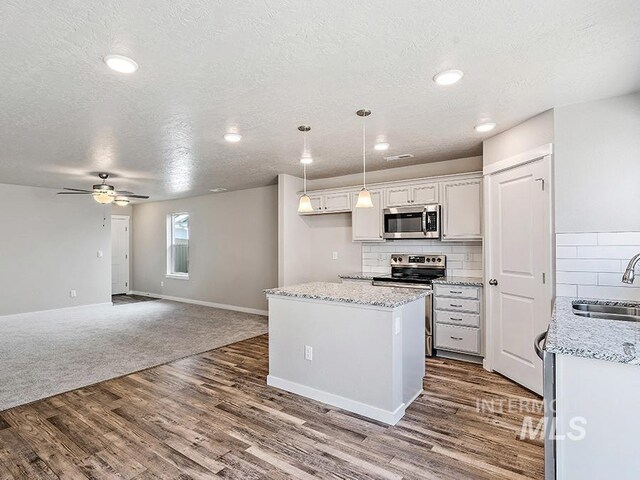 kitchen featuring white cabinetry, sink, hanging light fixtures, decorative backsplash, and appliances with stainless steel finishes